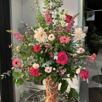 Tall mixed bouquet in a patterned vase with pink and cream blooms