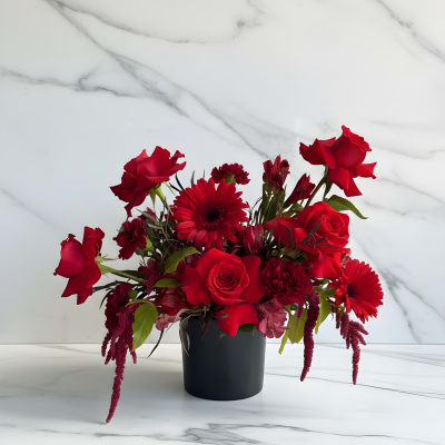 Red roses and gerbera daisies in a black vase