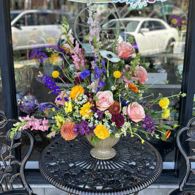 Colorful mixed flower arrangement in a beige vase on a black table