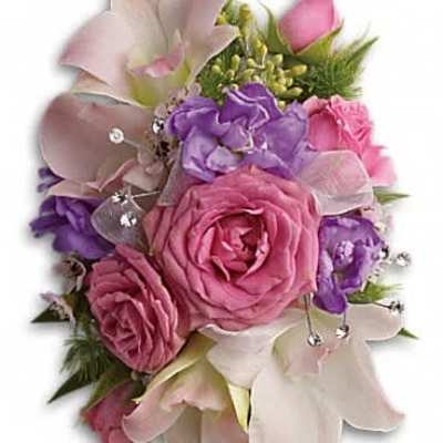Pink roses, white lilies, and purple blossoms arranged tightly with ribbon and crystal accents like a corsage
