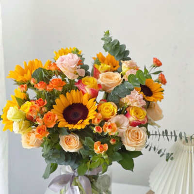 Bouquet of sunflowers and peach roses in a glass vase