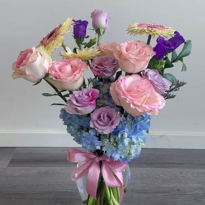 Pink and lavender roses with blue hydrangeas in a glass vase
