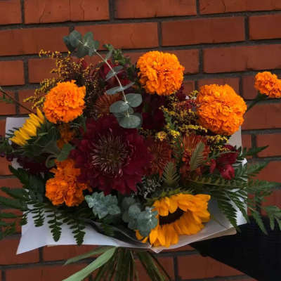 Bouquet of orange marigolds, sunflowers, and dark red blooms