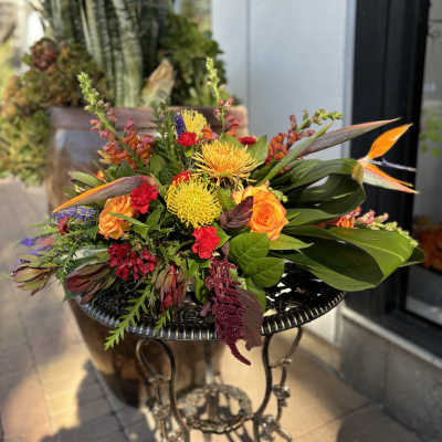 Colorful mixed bouquet with orange roses and yellow blooms on a metal table