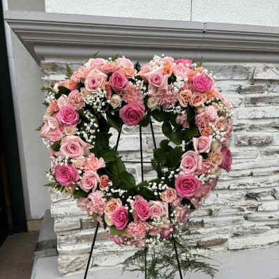 Heart-shaped floral wreath of pink roses and carnations on a stand