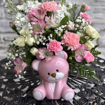Pink and white flower arrangement in a pink teddy bear container