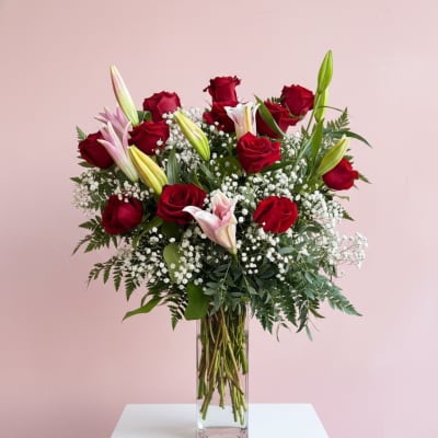 Red roses and lilies in a tall glass vase