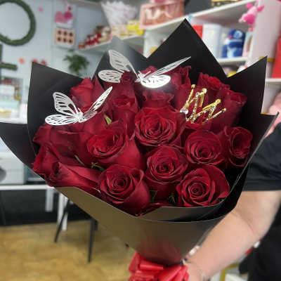 Bouquet of red roses wrapped in black paper with butterfly picks