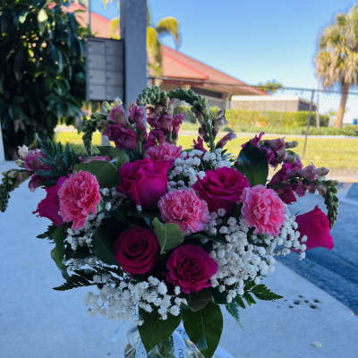 Pink roses and carnations in a glass vase with white filler flowers