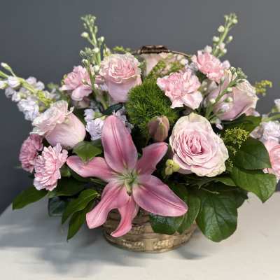 Pink roses and lilies arranged in a low basket