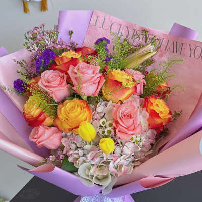 Bouquet of pink and yellow roses wrapped in lavender paper