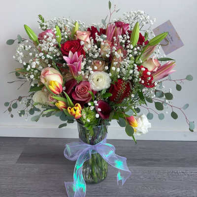 Mixed bouquet of roses, lilies, tulips, and baby's breath in a glass vase