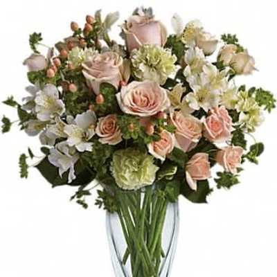 Tall vase arrangement of pale peach roses, white alstroemeria, and green carnations in a clear glass vase