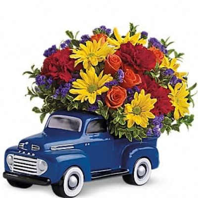 Bright mixed flowers arranged in a blue vintage truck ceramic vase