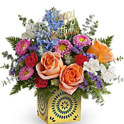 Colorful birthday flower arrangement with orange roses and mixed blooms in a yellow cube vase
