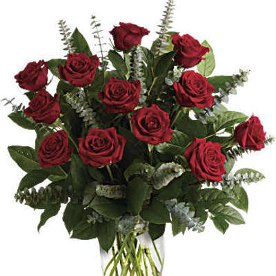 Tall arrangement of long-stemmed red roses in a clear glass vase.