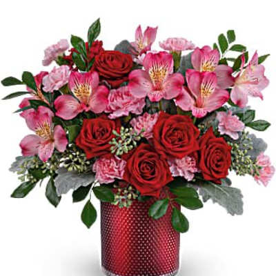 Red roses and pink mixed flowers in a red textured glass cylinder vase