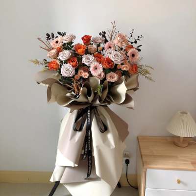 Large bouquet of peach and pink roses with paper wrapping