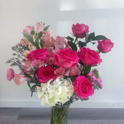 Pink roses and mixed blooms arranged in a clear glass vase