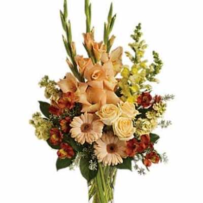 Tall peach and yellow mixed flower arrangement in a clear glass vase