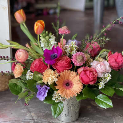 Mixed bouquet with pink roses, orange tulips, and a peach gerbera daisy in a metal vase