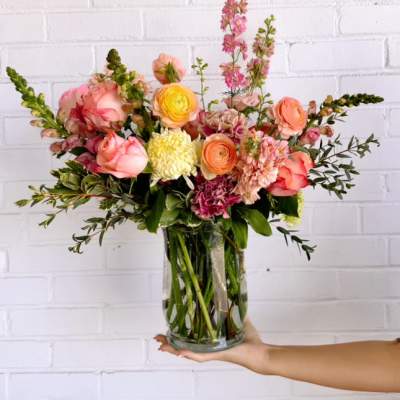 Mixed bouquet of pink, peach, and yellow flowers in a clear glass vase