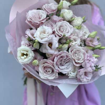 Bouquet of pale pink and white roses wrapped in lavender paper