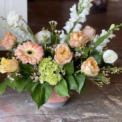 Peach roses and a pink gerbera daisy in a low vase arrangement
