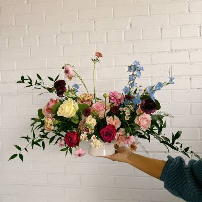 Mixed bouquet in a white vase with pink, blue, and cream flowers