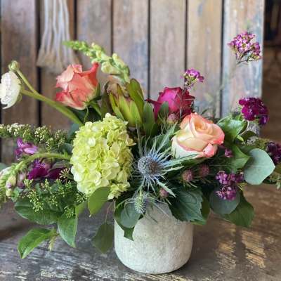 Mixed bouquet in a small white vase with pink and peach roses