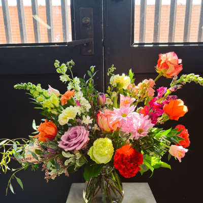 Mixed bouquet of roses, carnations, and daisies in a glass vase