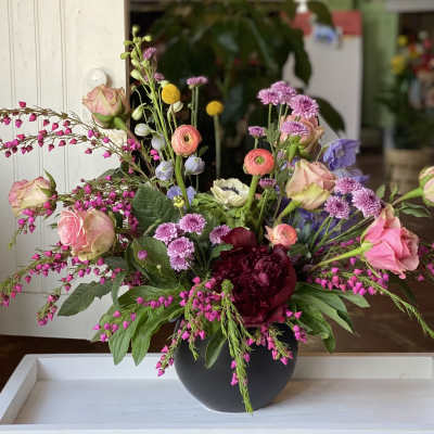 Mixed bouquet of pink, purple, and white flowers in a black vase