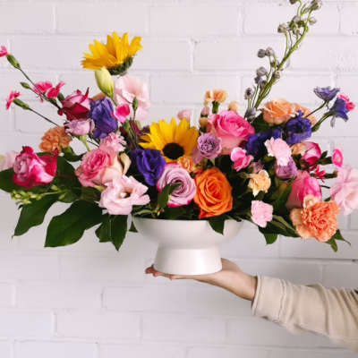 Colorful mixed flower arrangement in a white pedestal vase