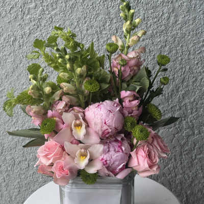 Pink bouquet with roses, peonies, orchids, and green accents in a glass vase