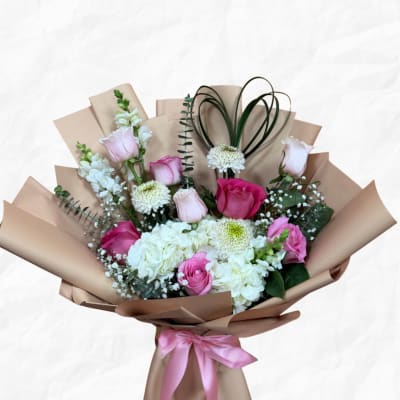 Pink and white rose bouquet wrapped in tan paper with a pink ribbon