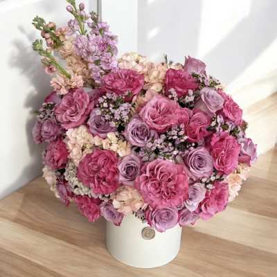 Pink and lavender roses arranged in a white hatbox