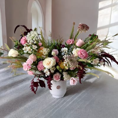 Large mixed bouquet in a white ribbed vase with pink and white blooms