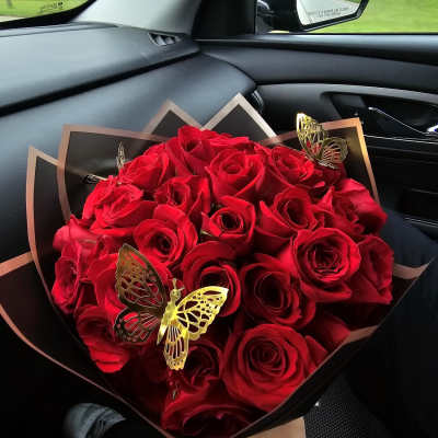 Bouquet of red roses wrapped in black paper with butterfly accents