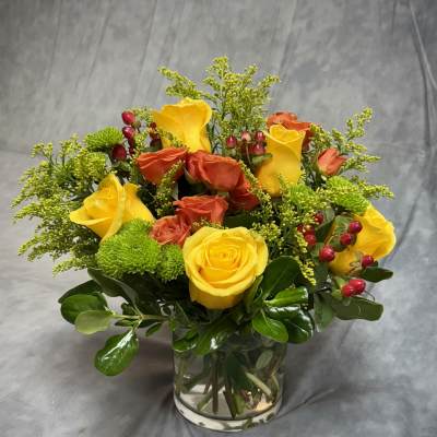 Yellow and orange roses arranged in a clear glass vase