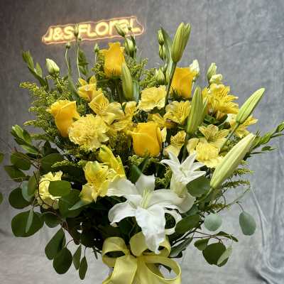 Yellow and white bouquet in a glass vase with a ribbon