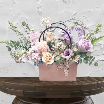 Pastel bouquet in a pink gift bag with roses and lavender flowers