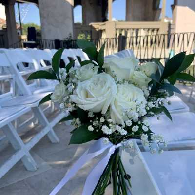 White rose bouquet with baby's breath and dark green leaves tied with a white ribbon