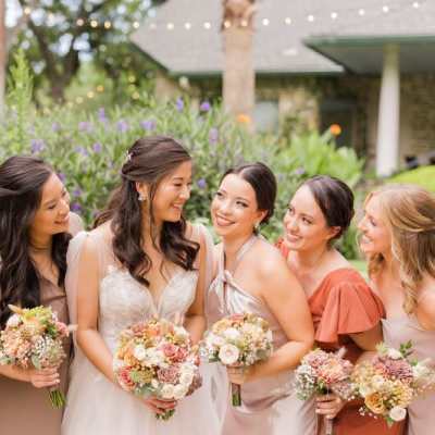 Bride and bridesmaids holding pastel flower bouquets outdoors