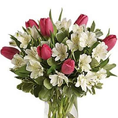 Pink tulips and white alstroemeria arranged in a clear glass vase