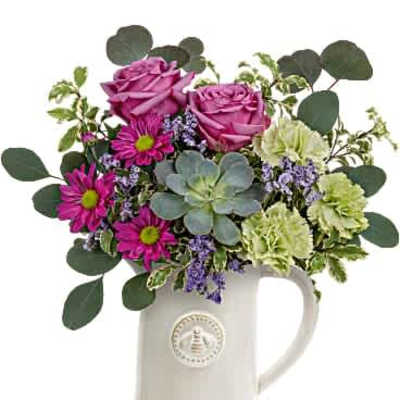 Mixed bouquet of pink roses, magenta daisies, green carnations, and a succulent in a white ceramic pitcher
