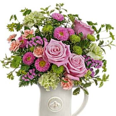 Pink and green mixed flower arrangement in a white ceramic pitcher
