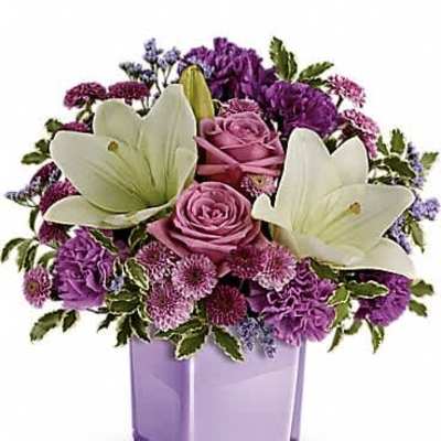 Purple and lavender bouquet with white lilies and roses in a light purple cube vase