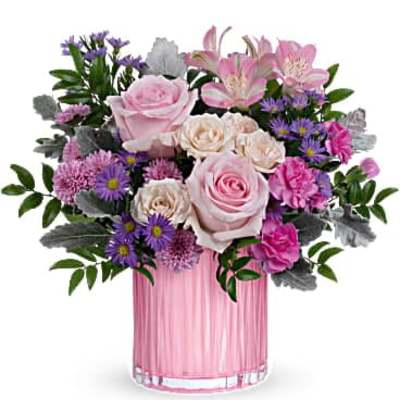Pink and purple mixed flower arrangement with roses and asters in a pink glass vase