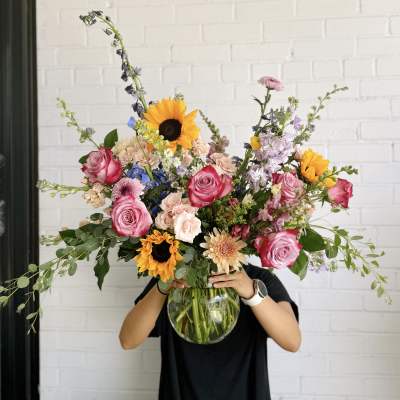 Large mixed bouquet in a glass vase with roses and sunflowers