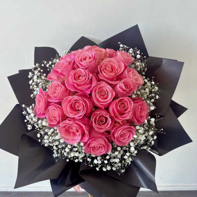 Bouquet of pink roses with white baby's breath in black wrap